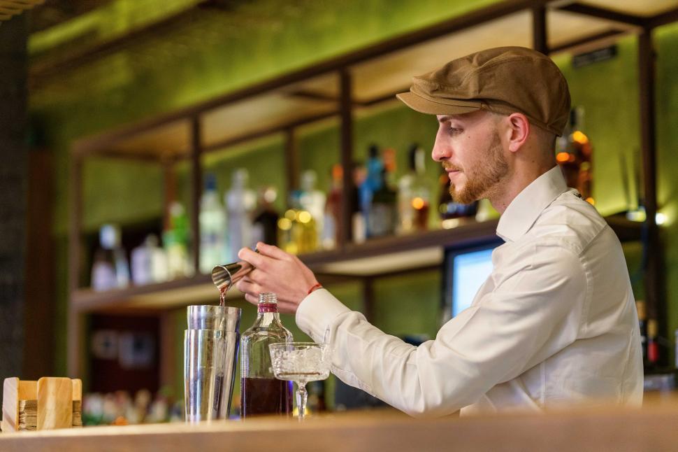 Free Image of Male barkeeper pouring alcohol into shaker 