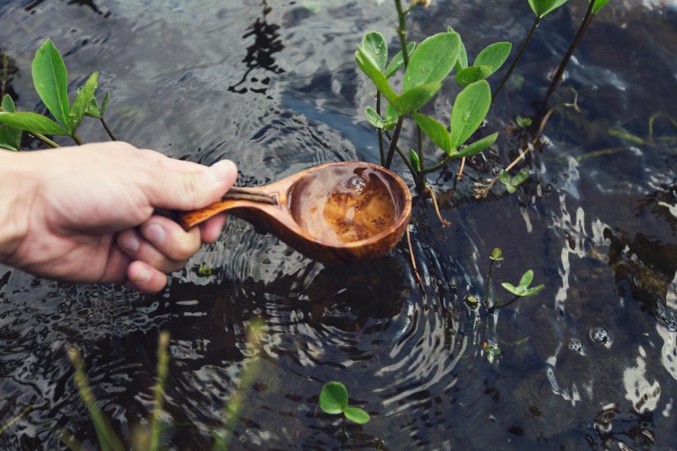 Free Image of A hand holding a wooden spoon in water 