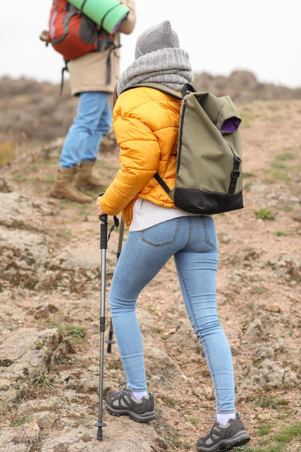 Free Image of A woman wearing a backpack and walking with a pair of poles 