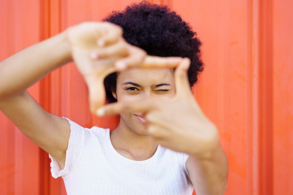 Free Image of Content black woman making frame gesture near wall 