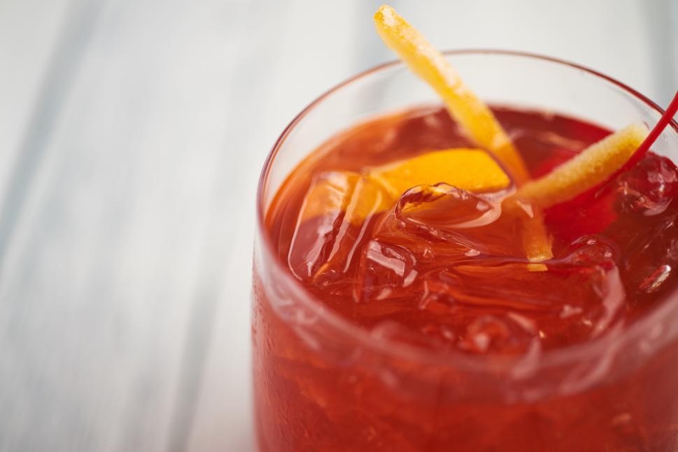 Free Image of A glass of red liquid with a slice of orange and ice 