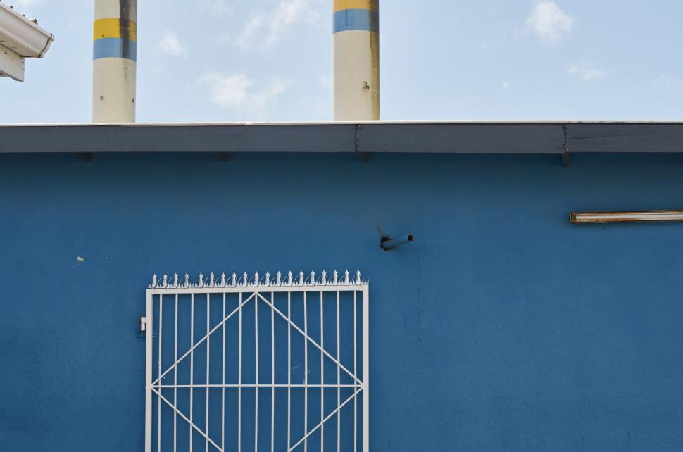 Free Image of A blue wall with a gate and smoke stacks 