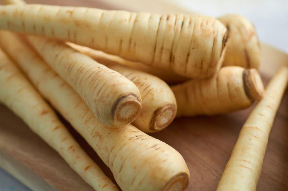 Free Image of A pile of parsnips on a wooden surface 