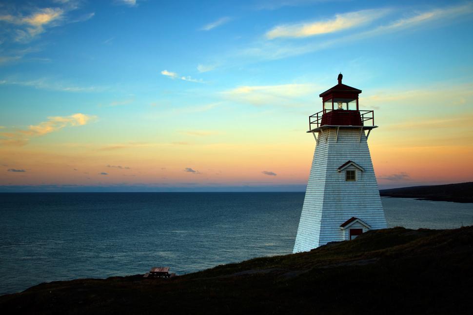 Free Image of A lighthouse on a hill by the water 