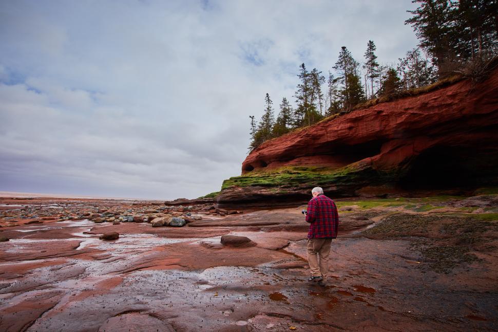 Free Image of A man standing on a rocky beach 
