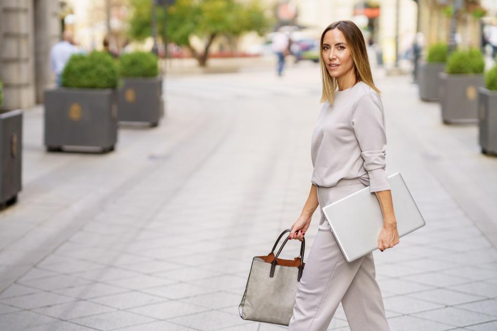 Free Image of Stylish female entrepreneur with netbook strolling on city street 