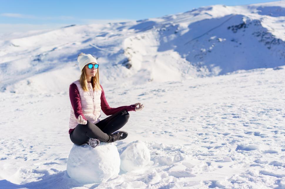 Free Image of Cheerful woman sitting with lotus pose on snow 