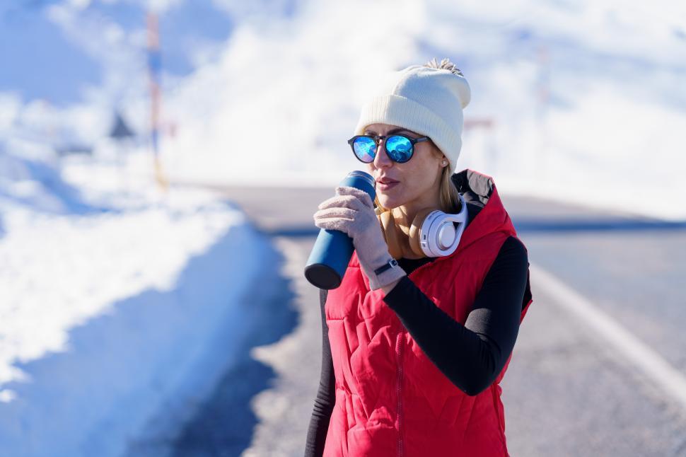 Free Image of Sportive lady with thermos bottle in winter nature 