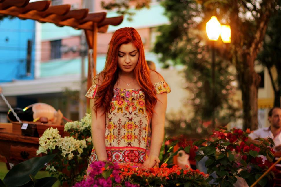Free Image of A woman standing in front of a flower bed 