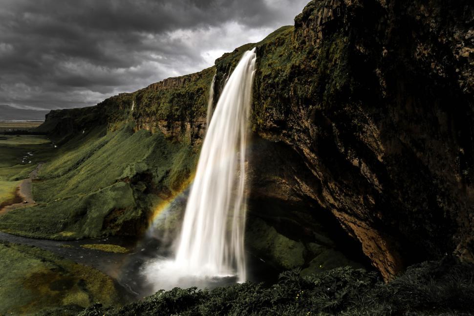 Free Image of A waterfall with a rainbow over a cliff 