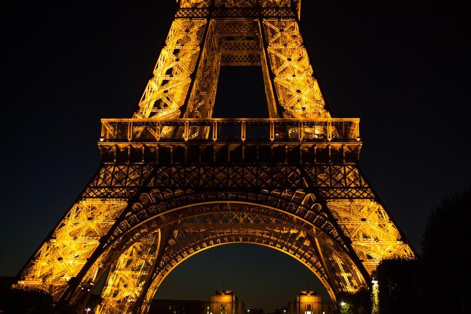 Free Image of A large metal tower lit up at night with eiffel tower in the background 
