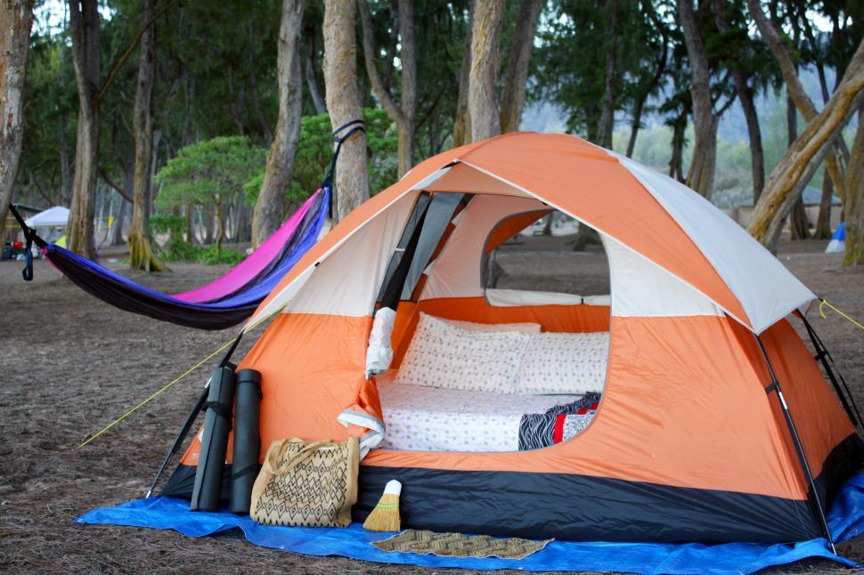 Free Image of A tent with a bed and blankets in the woods 