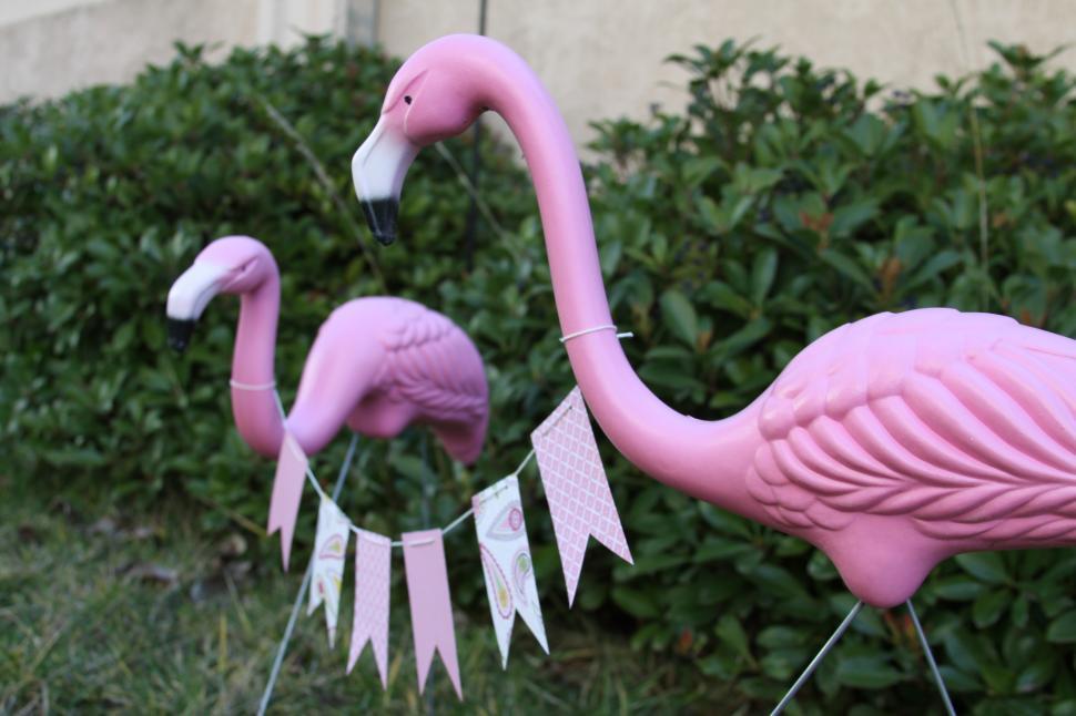Free Image of A pink flamingo statues in front of a bush 