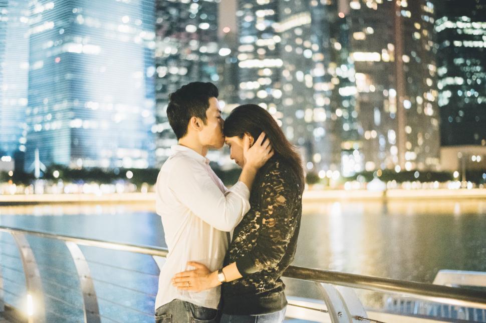 Free Image of A man and woman kissing on a bridge 