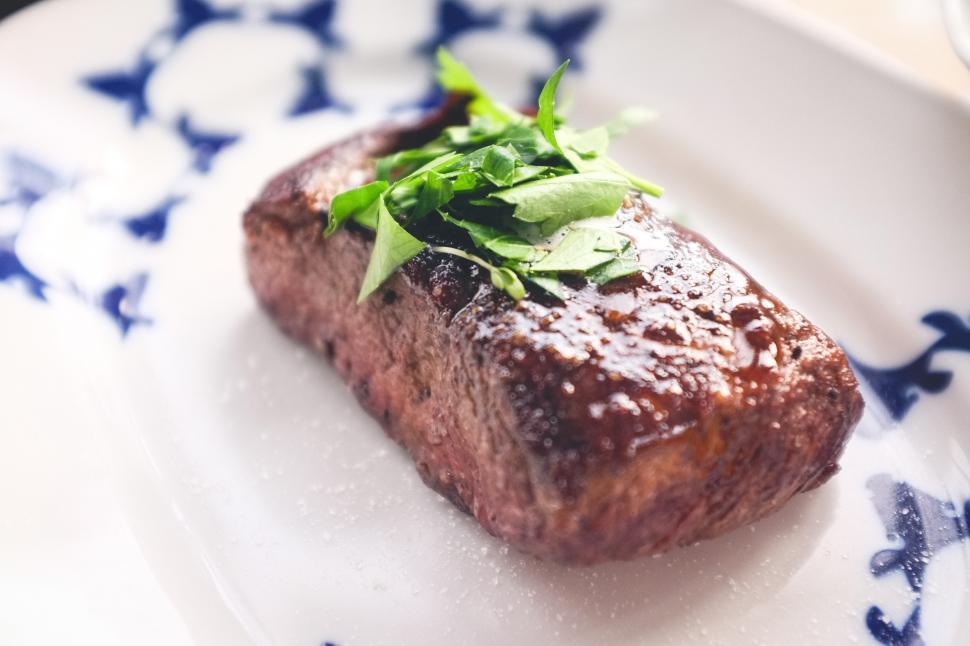 Free Image of A piece of meat with green leaves on top 