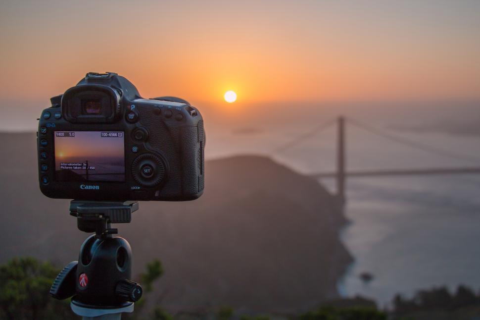 Free Image of A camera on a tripod with a bridge in the background 