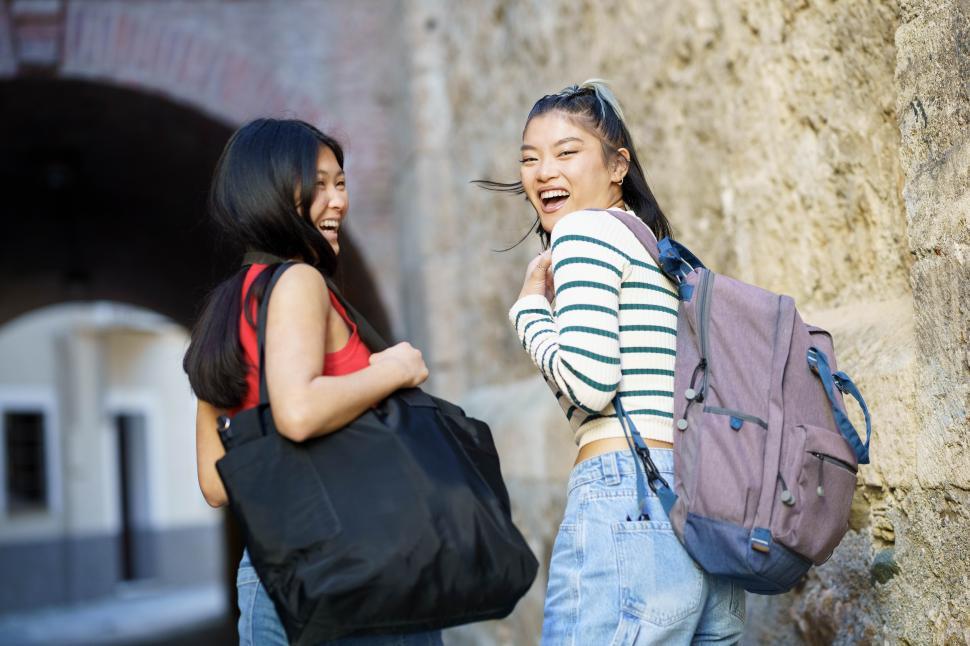 Free Image of Cheerful Asian women with bags in street 