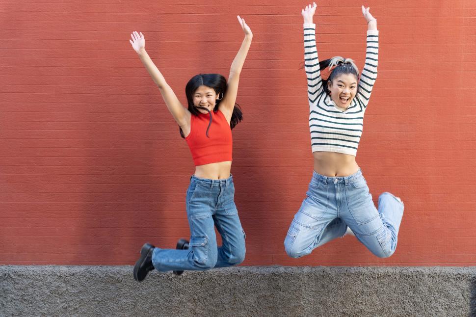 Free Image of Excited Asian girlfriends jumping with arms up 