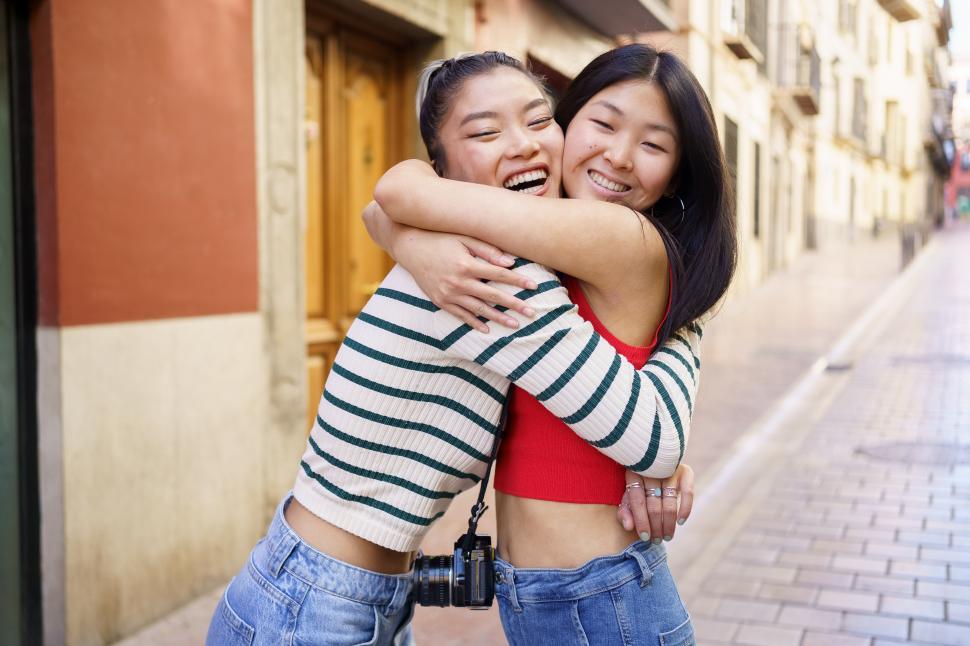 Free Image of Asian girlfriends hugging on city street 