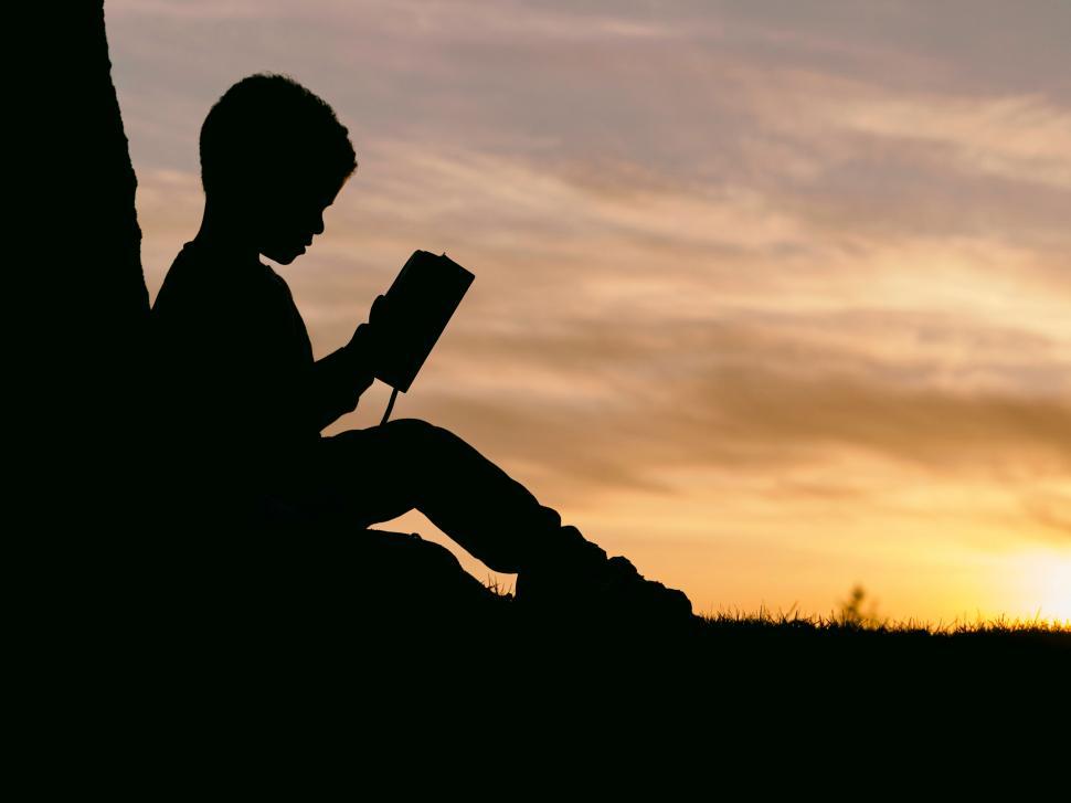 Free Image of A silhouette of a child reading a book 