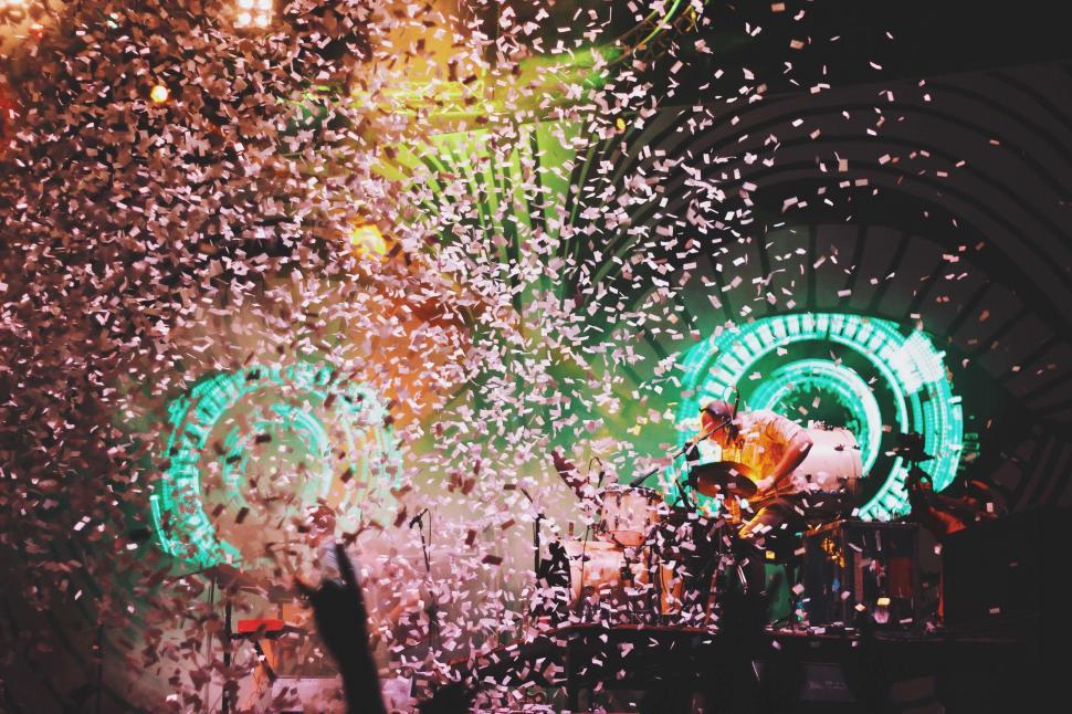 Free Image of A man playing a guitar on a stage with confetti flying around him 