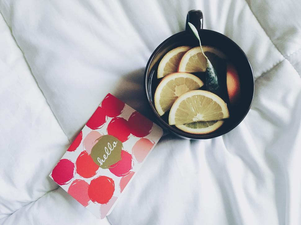 Free Image of A cup of water with lemon slices and a book 