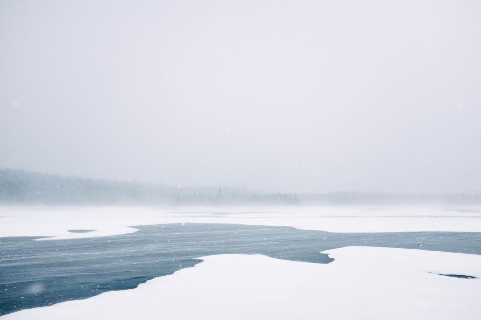Free Image of A body of water with snow and trees in the background 