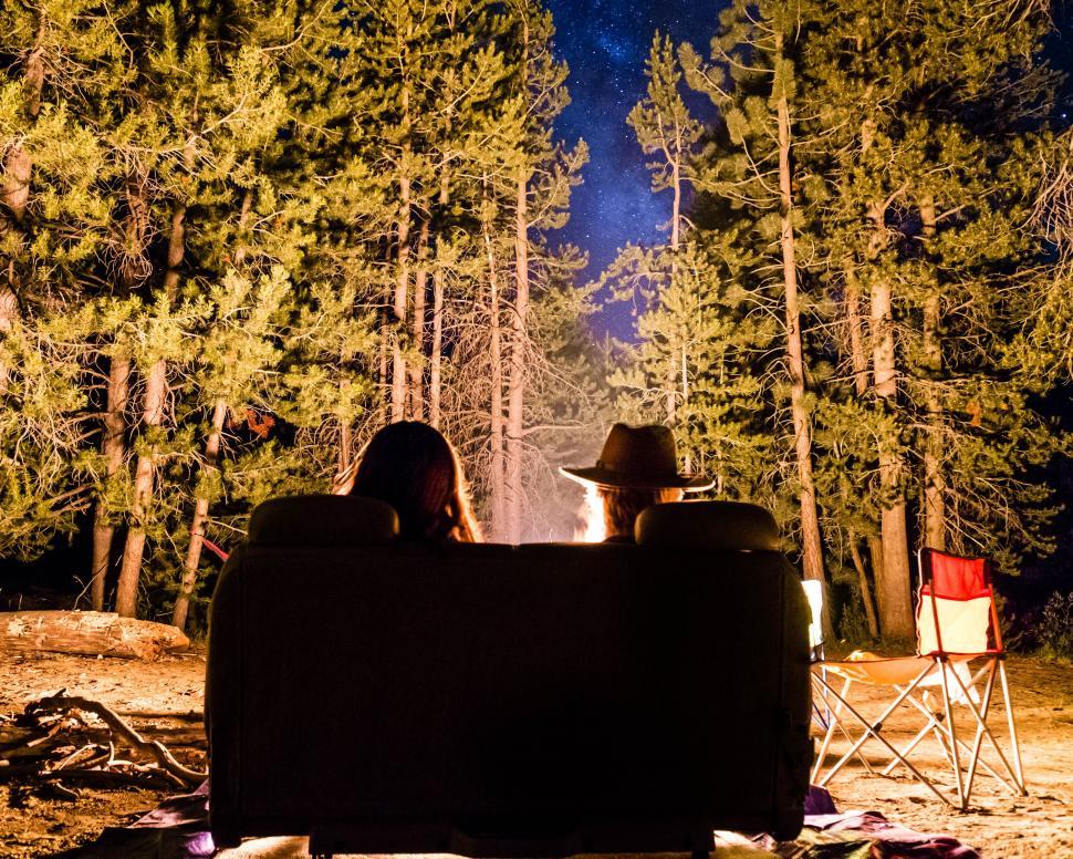 Free Image of A couple of people sitting on a couch in front of a campfire 