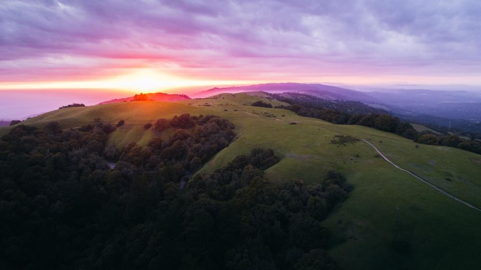 Free Image of A sunset over a green hill 