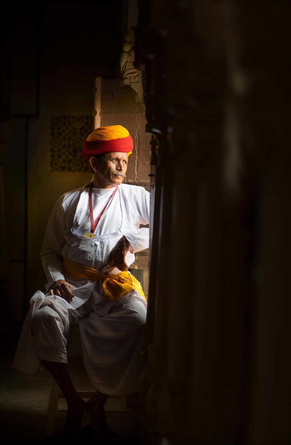 Free Image of A man in a turban sitting in a doorway 