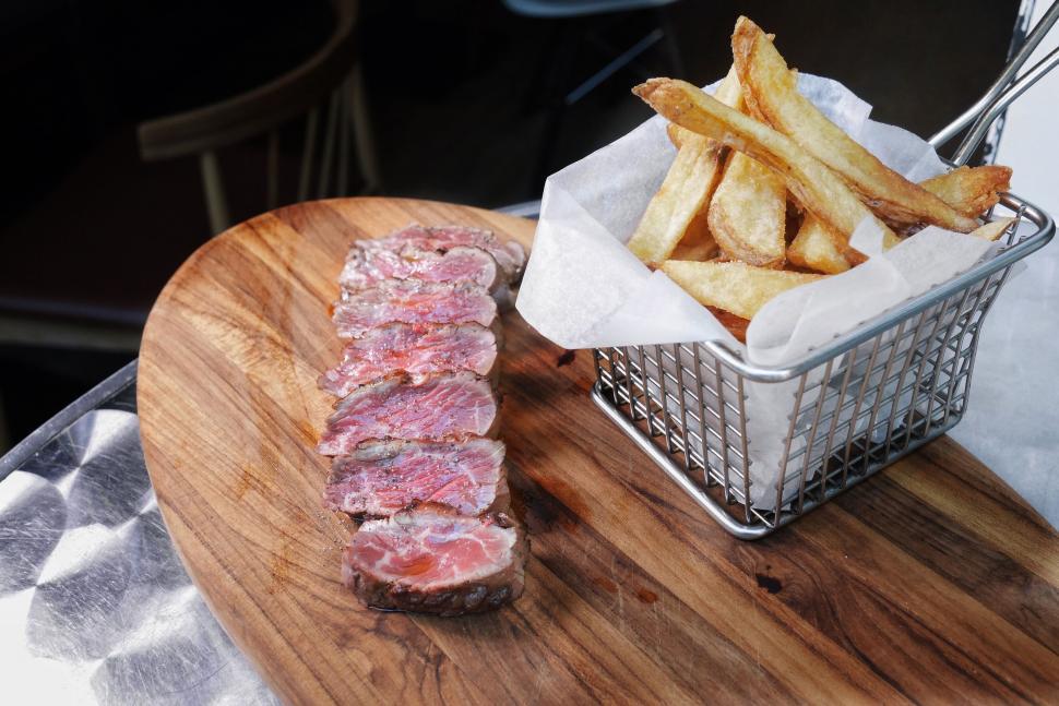 Free Image of A basket of french fries and steak on a wooden board 