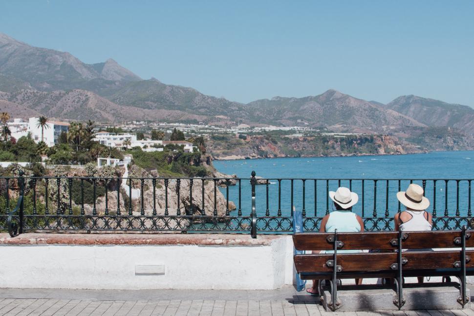 Free Image of A person sitting on a bench overlooking a body of water 