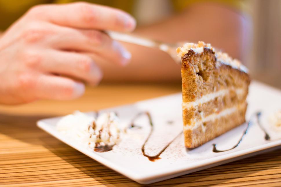 Free Image of A hand holding a fork to a piece of cake 