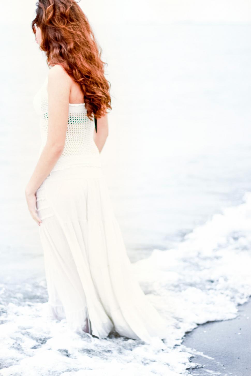 Free Image of A woman in a white dress standing in the water 