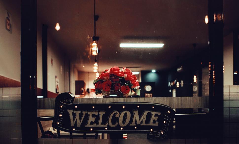 Free Image of A welcome sign with flowers in it 