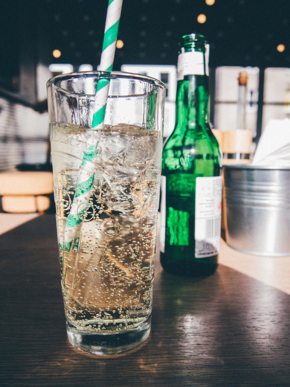 Free Image of A glass of liquid with a straw and a green bottle 