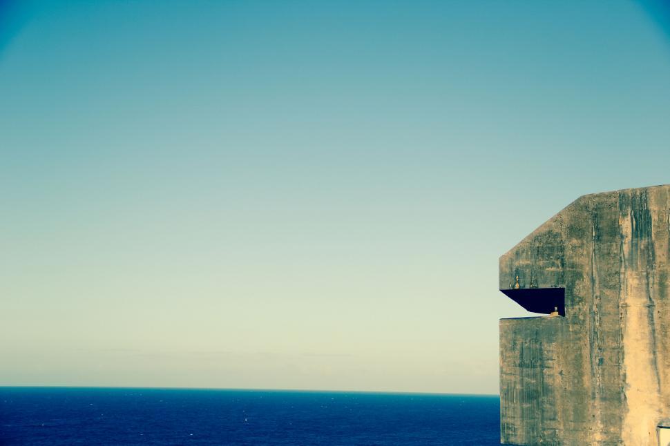 Free Image of A concrete structure with a blue sky and water in the background 