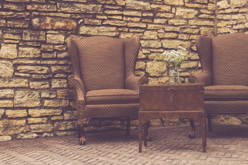 Free Image of Two chairs and a table in front of a stone wall 