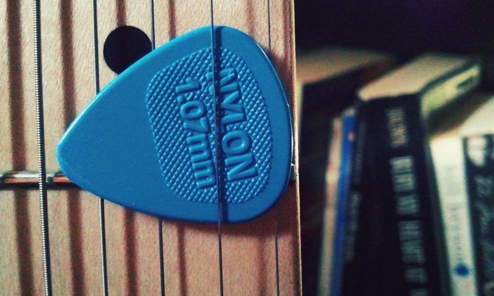 Free Image of A blue guitar pick on a wood surface 