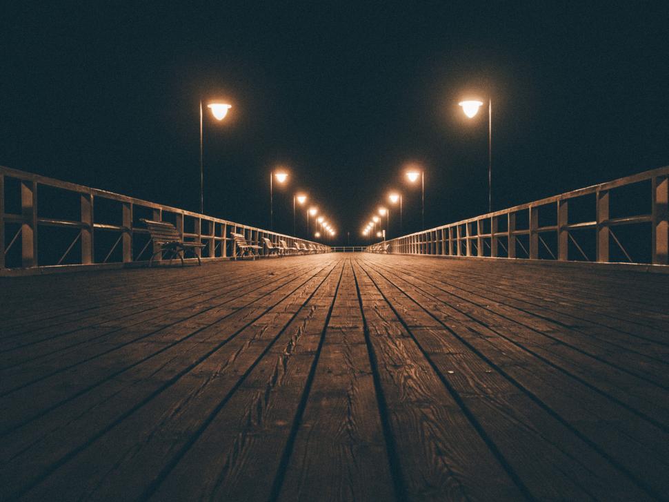 Free Image of A wooden walkway with lights at night 