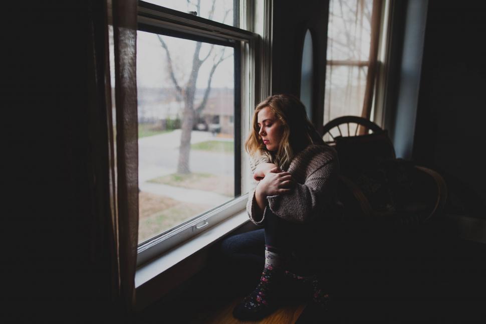 Free Image of A woman sitting on a window sill 