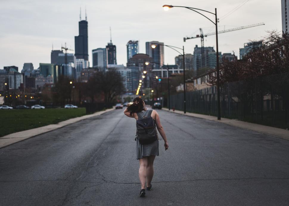 Free Image of A woman walking down a street with a city in the background 