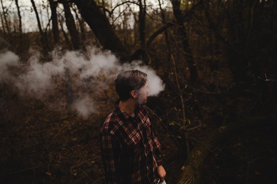 Free Image of A man standing in the woods with smoke coming out of his head 