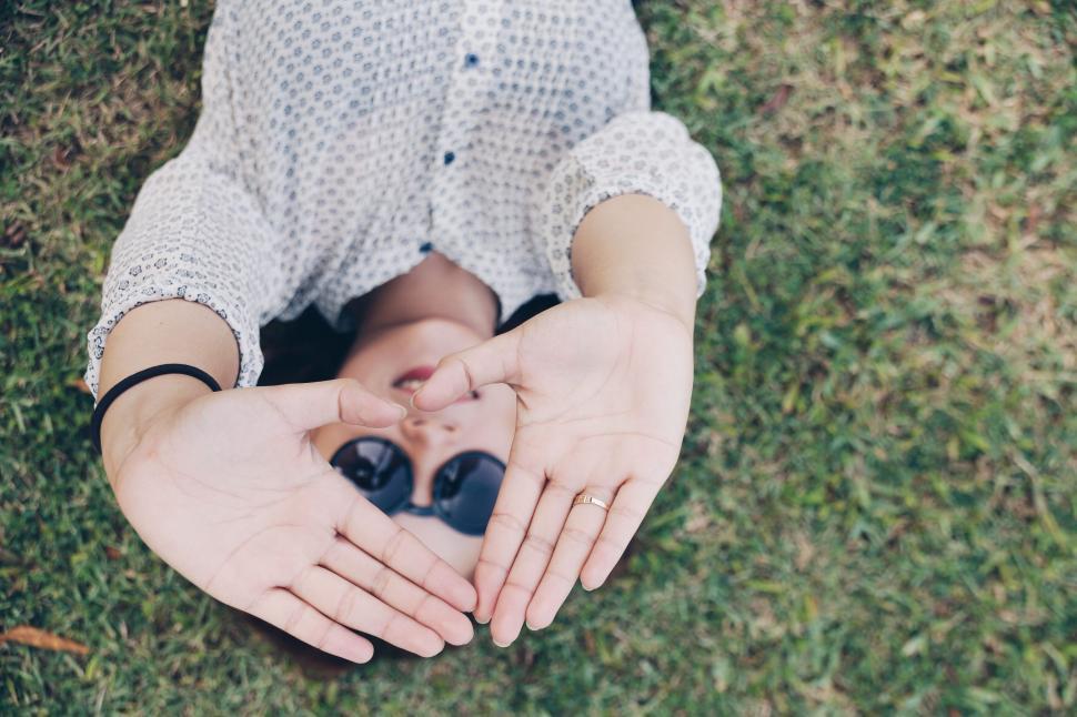 Free Image of A person lying on the grass with their hands in front of their face 