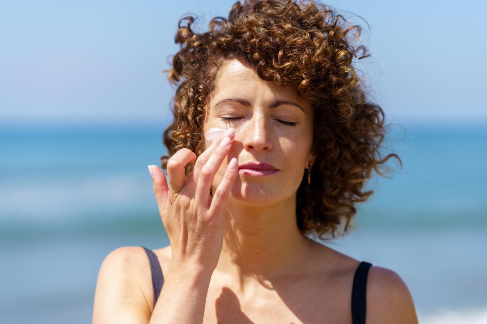Free Image of Sensual woman applying sunscreen on face 
