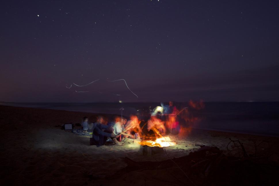 Free Image of A group of people around a fire on a beach at night 