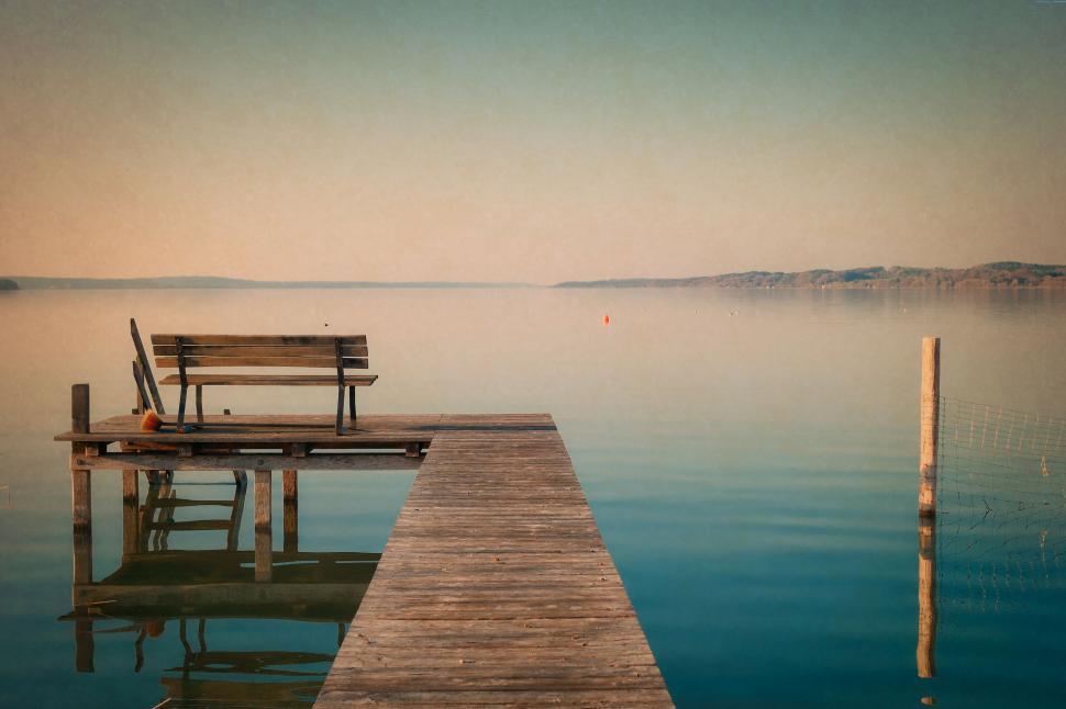 Free Image of A wooden bench on a dock over water 