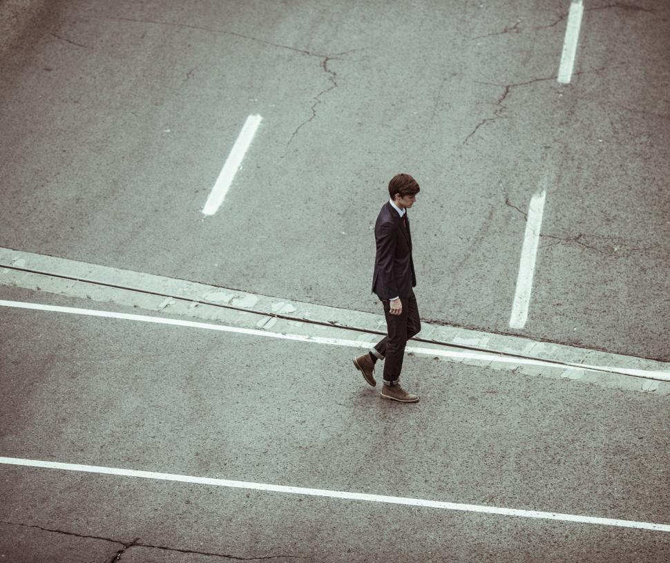 Free Image of A man walking across a street 