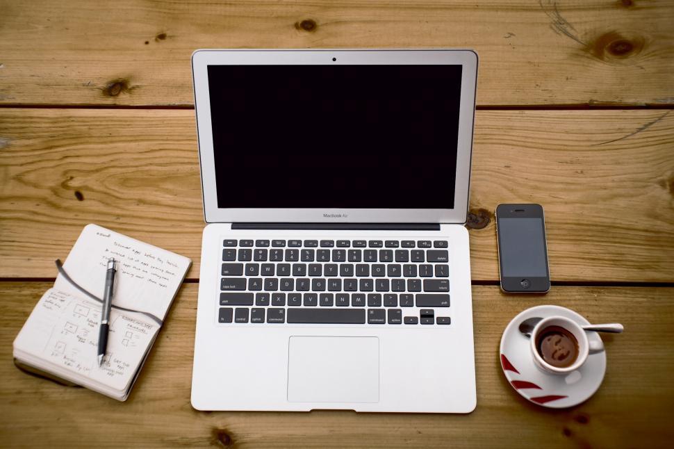 Free Image of A laptop and a cup of coffee and a phone on a table 