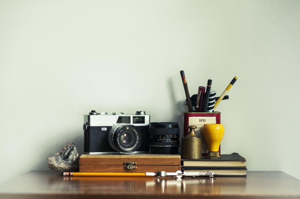 Free Image of A camera and pencils on a desk 